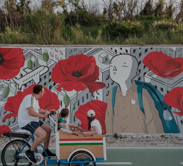 Murale di Millo con un uomo e una bambina in bicicletta che lo osservano